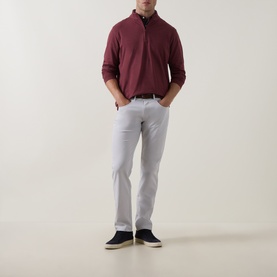 Model wearing Peter Millar bordeaux half-zip sweatshirt with white trousers and navy trainers.