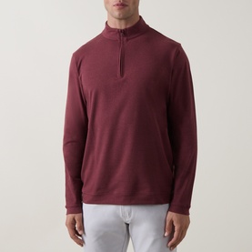 Model wearing Peter Millar bordeaux quarter-zip sweatshirt with mock neck collar, styled with white trousers.