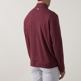 Model wearing Peter Millar bordeaux quarter-zip sweat, rear view, paired with light grey trousers.