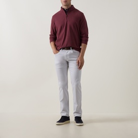 Model wearing Peter Millar Bordeaux quarter-zip sweatshirt with white trousers and navy shoes.