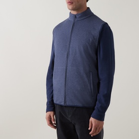 Model wearing Peter Millar navy zip-up gilet vest over a navy long-sleeve top, with dark trousers.