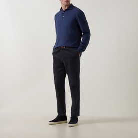 Model wearing Peter Millar navy cotton long-sleeve polo sweat, styled with dark charcoal trousers and navy suede trainers.