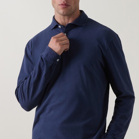 Model wearing Peter Millar navy long-sleeve polo shirt in cotton-spandex blend, buttoned at collar, slim fit.