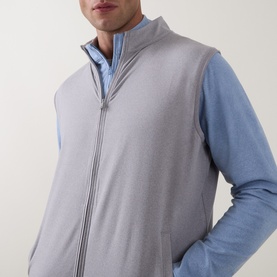 Model wearing Peter Millar Gale Grey zip-up gilet, styled with a blue long-sleeve top underneath.
