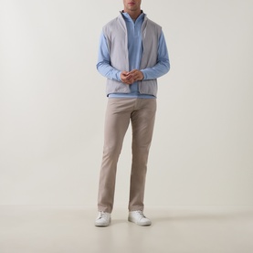 Model wearing Peter Millar Gale Grey zip-up gilet over light blue shirt and beige chinos with white trainers.