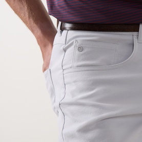 Model wearing Peter Millar eb66 Mid-Rise Straight Leg Jeans in grey, five-pocket style with belt loops, styled with a dark leather belt.