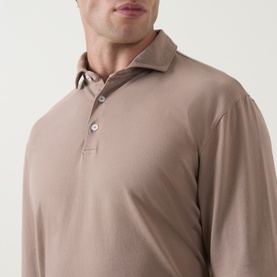 Model wearing Peter Millar sawgrass long-sleeve polo sweatshirt in warm taupe, featuring a classic collar and three-button placket.