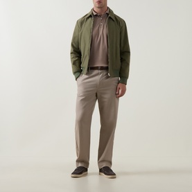 Model wearing Peter Millar Sawgrass sweat with olive zip jacket, taupe trousers and dark loafers