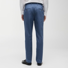 Model wearing Tommy Hilfiger trousers in Aegean Sea, rear view, tailored fit with belt loops, styled with a white shirt and black shoes.