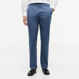 Model wearing Tommy Hilfiger trousers in Aegean Sea blue, slim fit with belt loops, styled with white shirt and black loafers.
