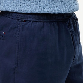 Model wearing Tommy Hilfiger Carbon Navy drawstring trousers with elasticated waist, styled with a light blue textured top.