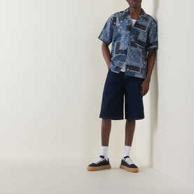 Model wearing Dickies dark navy patchwork print short-sleeve shirt, styled with navy shorts and black flatform trainers.