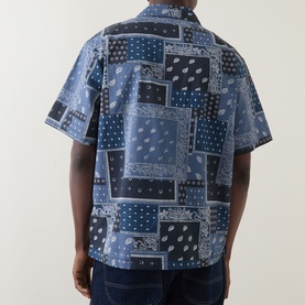 Model wearing Dickies dark navy patchwork bandana print short-sleeve shirt, shown from behind, paired with dark jeans