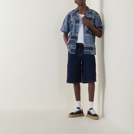 Model wearing Dickies dark navy bandana-print short-sleeve shirt, styled with navy denim shorts, white tee and black trainers.