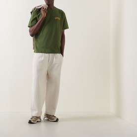 Model wearing Dickies Cypress green crew neck T-shirt with cream wide-leg trousers and grey trainers