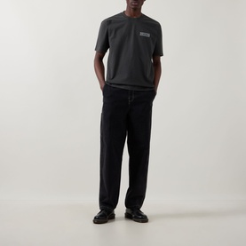 Model wearing Dickies Buchtell Logo T-Shirt in black, crew neck with chest logo, styled with black relaxed trousers and loafers.