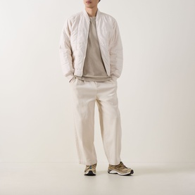 Model wearing Dickies Darrtown Logo T-Shirt in Eucalyptus, styled with a white quilted bomber jacket, cream trousers, and taupe trainers.