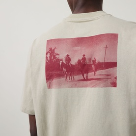 Model wearing Dickies Millville Logo T-Shirt in Eucalyptus, showing back with red Western horseback riding graphic print.