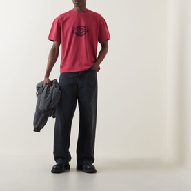 Model wearing Dickies Garnet Crew Neck T-shirt with dark wide-leg trousers, holding a grey jacket.