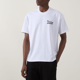 Model wearing Dickies white crew neck T-shirt with small chest logo print, styled with black trousers.