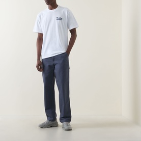 Model wearing Dickies white crew neck T-shirt with navy trousers and grey trainers.