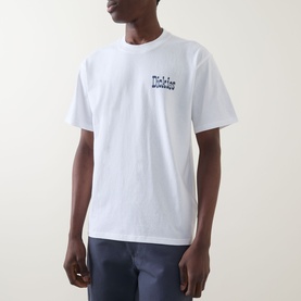 Model wearing Dickies white cotton crew neck T-shirt with small chest graphic print, styled with navy trousers.