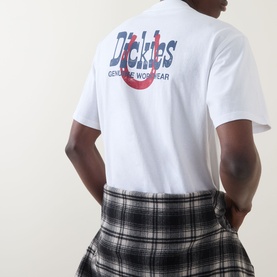 Model wearing Dickies white crew neck T-shirt, back view showing logo graphic print, styled with black and white plaid skirt.