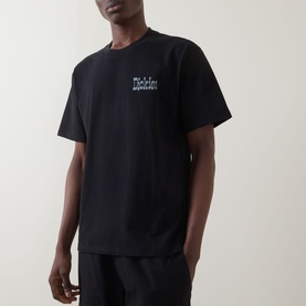 Model wearing Dickies black crew neck T-shirt with small chest logo graphic, paired with black trousers.