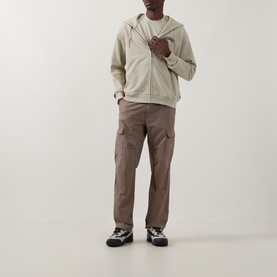 Model wearing Dickies Bettsville Logo Zip Hoodie in Eucalyptus with brown cargo trousers and trail trainers.