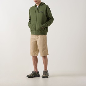 Model wearing Dickies Bettsville Logo Zip Hoodie in Cypress, styled with beige shorts and grey trainers
