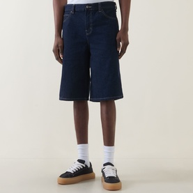 Model wearing Dickies rinsed denim shorts with white socks and black flatform trainers