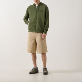Model wearing Dickies 958 Loose Denim Shorts in Eucalyptus, styled with a green zip-up hoodie and grey trail trainers.