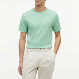 Model wearing Tommy Hilfiger cut grass green crew neck T-shirt with small logo embroidery, styled with cream tailored trousers