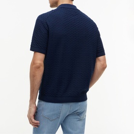 Model wearing Tommy Hilfiger Carbon Navy textured knit polo shirt, short sleeves, rear view, styled with light blue jeans.