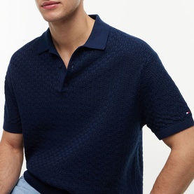 Model wearing Tommy Hilfiger Carbon Navy textured knit polo shirt with open collar and short sleeves, Tommy flag logo visible