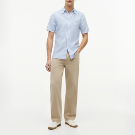 Model wearing Tommy Hilfiger blue spell striped short-sleeve shirt with beige chinos and white shoes.