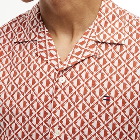 Model wearing Tommy Hilfiger shirt in Rusty Ochre geometric allover print, camp collar, with small logo embroidery at chest.