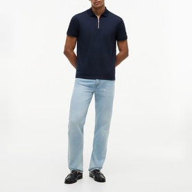 Model wearing Tommy Hilfiger navy blue zip-neck polo shirt, styled with light wash straight-leg jeans and black loafers.