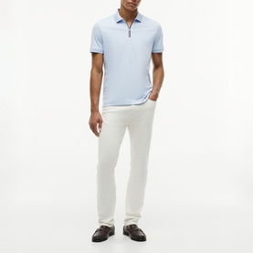 Model wearing Tommy Hilfiger Breezy Blue zip-neck polo shirt, styled with white trousers and dark loafers