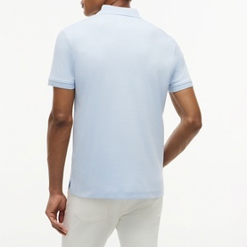 Model wearing Tommy Hilfiger Breezy Blue polo shirt, back view, with white tipped collar and cuffs, styled with white trousers.