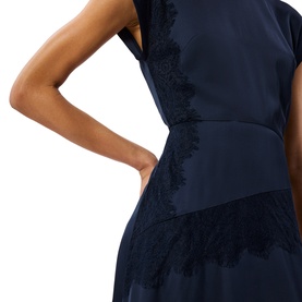 Model wearing Whistles blue dress with floral lace trim detail at waist and hem, cap sleeve visible at shoulder.