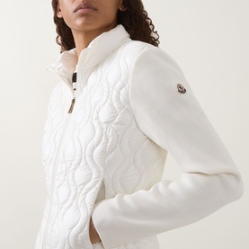 Model wearing Moncler natural cardigan with quilted front panel, zip neckline, and logo badge on sleeve