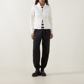 Model wearing Moncler natural quilted cotton cardigan with black trousers, striped top, and black loafers.