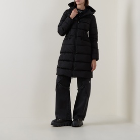 Model wearing Moncler black quilted longline down coat with hood, styled with black wide-leg trousers and chunky boots.