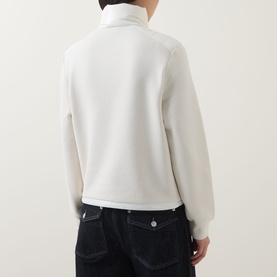 Model wearing Moncler natural cardigan, back view, with dark navy jeans. Zip-up style with high collar.