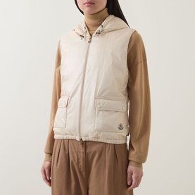 Model wearing Moncler beige hooded gilet with front zip and patch pockets, styled with camel knit top and wide-leg trousers