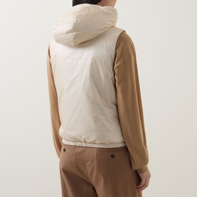 Model wearing Moncler beige hooded gilet, back view, styled with a camel long-sleeve top and matching trousers.
