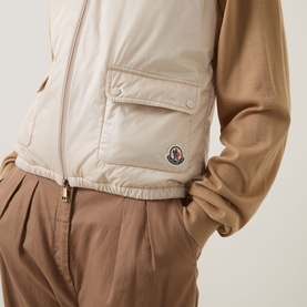 Model wearing Moncler beige gilet with cargo pocket detail, styled with camel long-sleeve top and taupe trousers