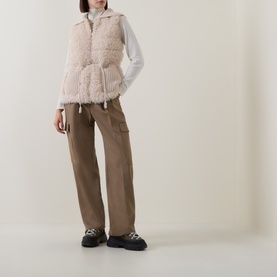 Model wearing Moncler beige sherpa gilet with drawstring hem, styled with white long-sleeve top, khaki cargo trousers and black chunky loafers