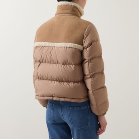 Model wearing Moncler brown quilted down jacket with contrast wool panels, cropped fit, styled with blue jeans. Rear view.